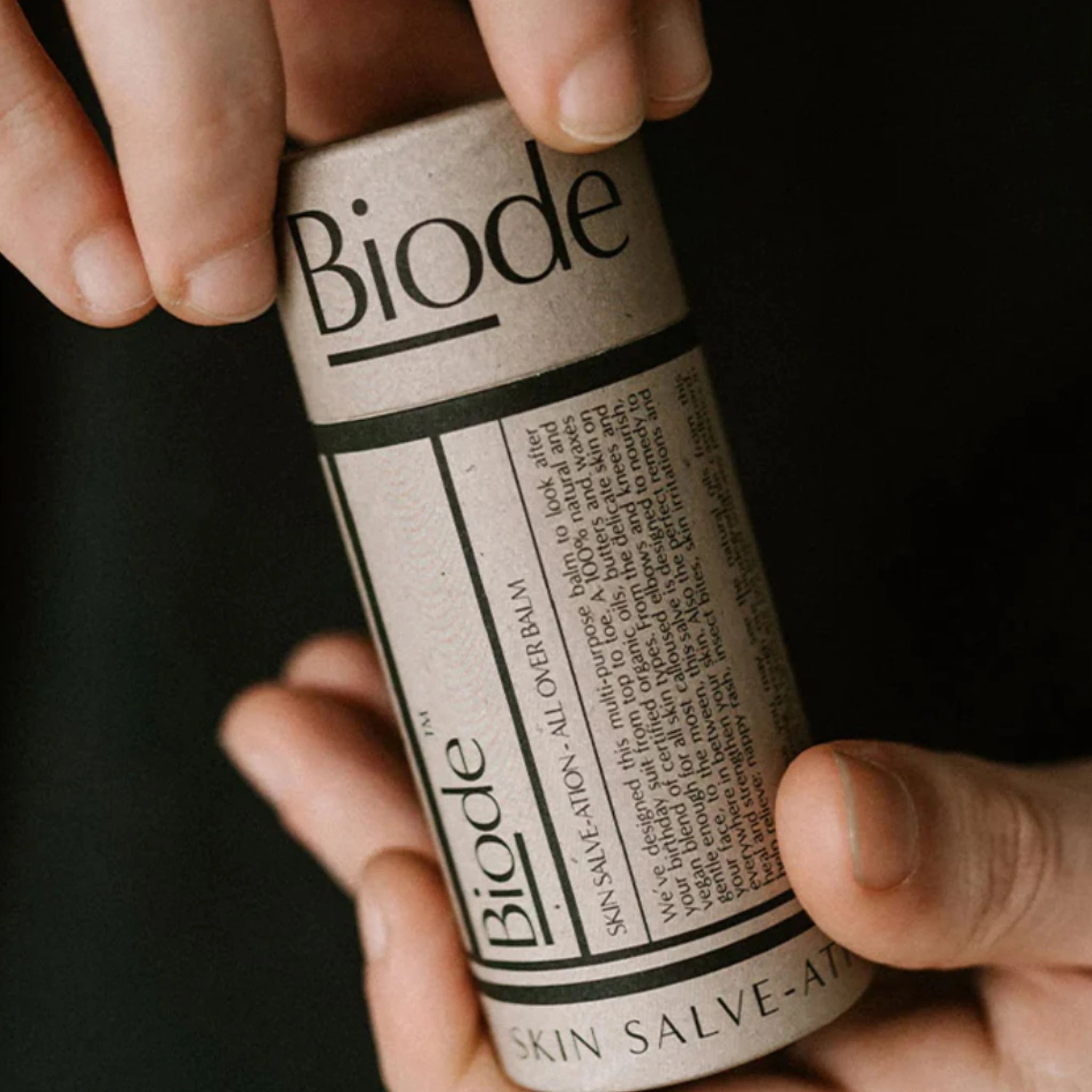Hands holding the 60G home compostable tube of the Biode Skin Salve-ation multipurpose balm.