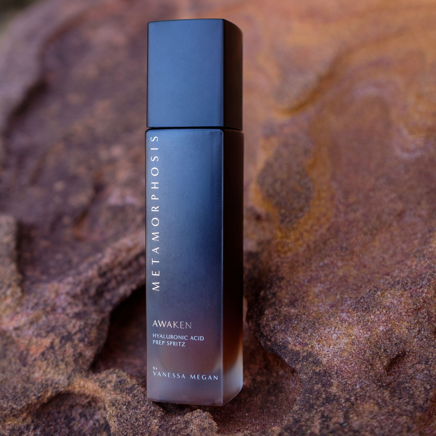 Metamorphosis Awaken Hyaluronic Acid Prep Spritz by Vanessa Megan, styled against a natural earthy rock backdrop – 100% natural facial mist for peri to post menopausal skin.