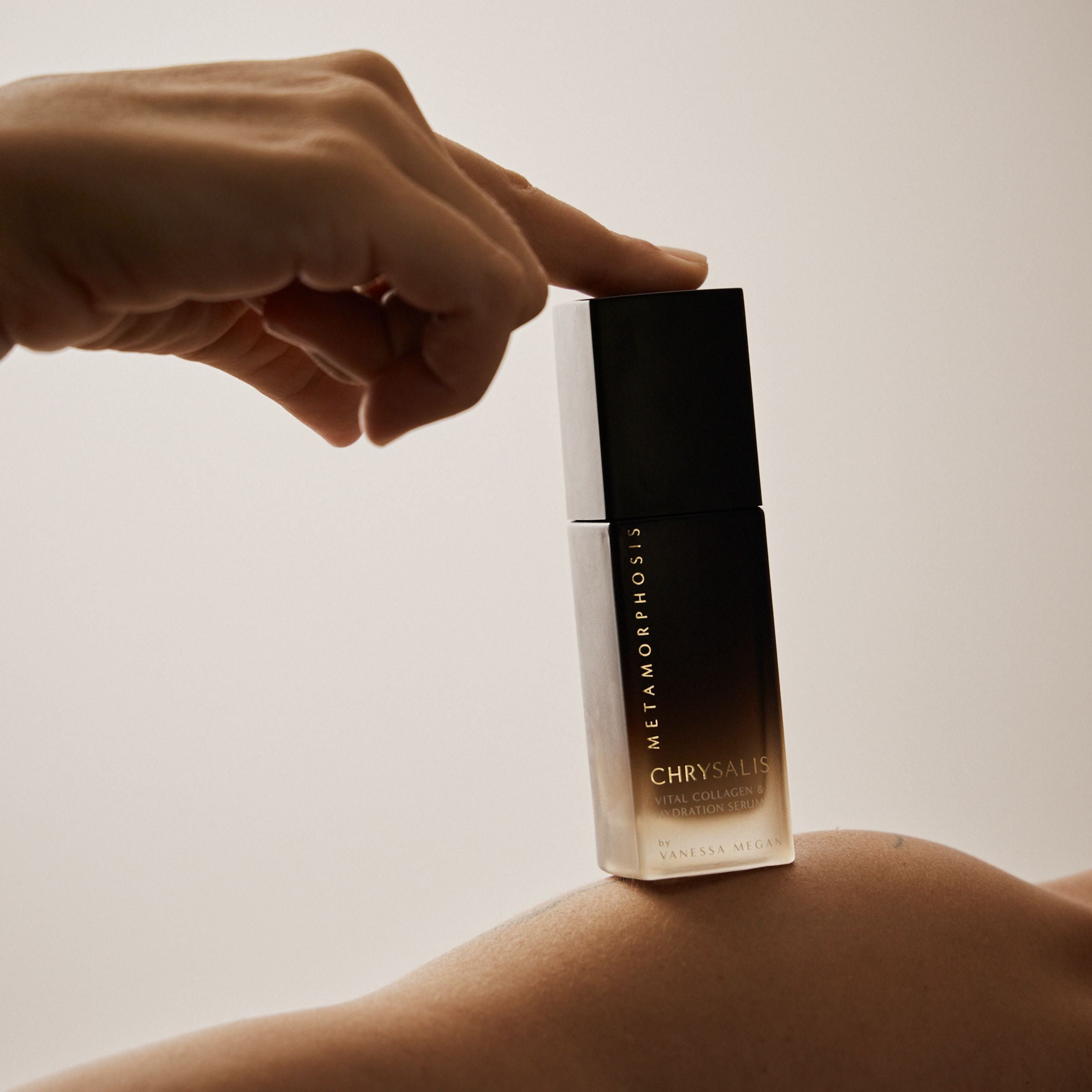 Metamorphosis Chrysalis Vital Collagen & Hydration Serum by Vanessa Megan, balanced on a bare shoulder with a hand gently pressing the lid – natural skincare for menopausal skin.