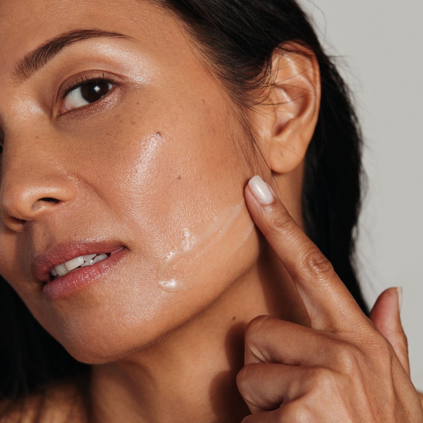 Close-up of a woman with menopausal skin applying Metamorphosis Peptide Amino Acid Serum to her cheek