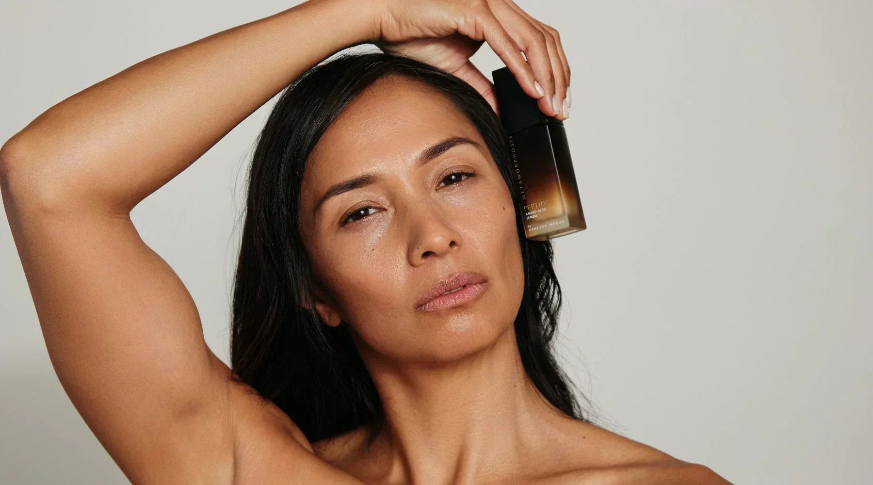 Woman with glowing skin holding Vanessa Megan Peptide Amino Acid Serum from the Metamorphosis Skincare range, natural peptide serum for mature skin.