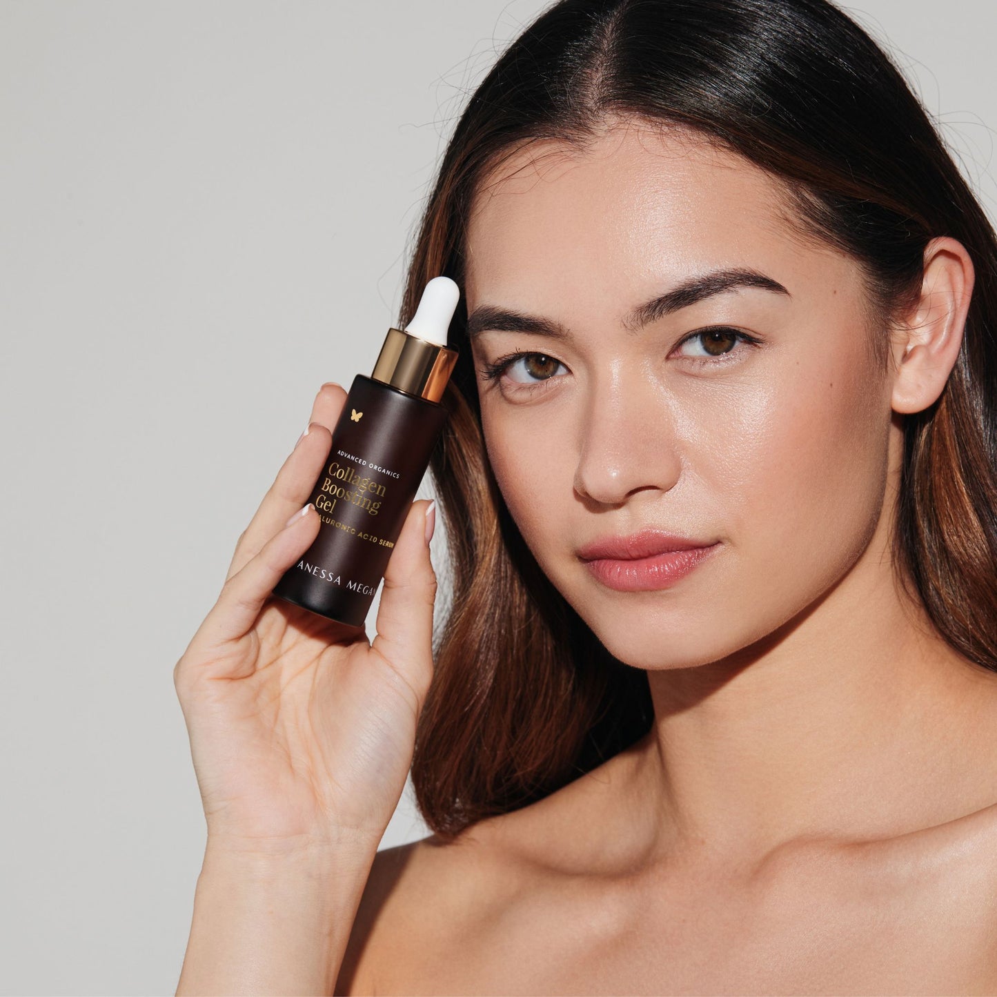 Woman holding Vanessa Megan Collagen Boosting Gel Hyaluronic Acid Serum with glowing skin.