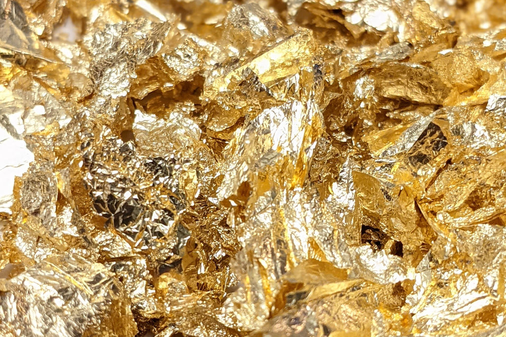 A close-up of 24k gold flakes used in beauty, health and wellness to add a radiant glow, reduce redness, and support anti-aging  by reflecting light and boost then effectiveness of other nutrients when paired with other active ingredients.