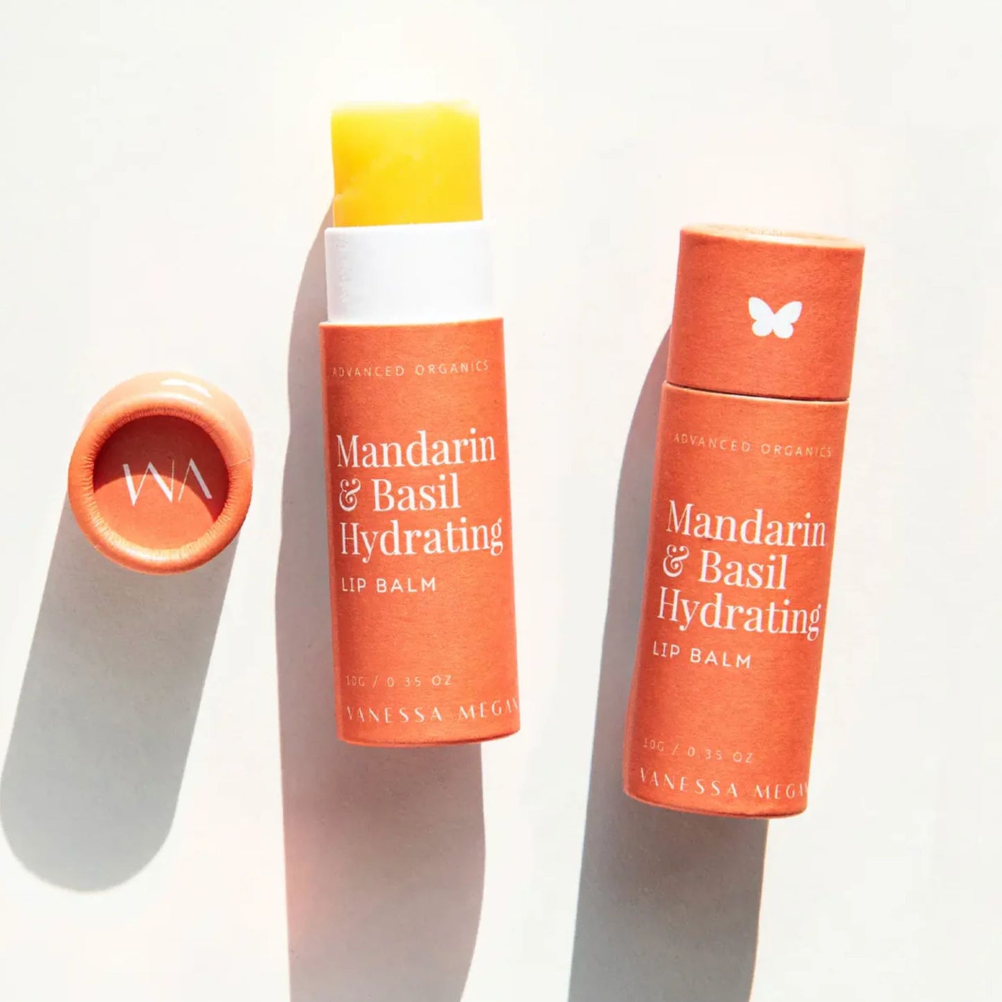 Two tubes side by side of the Vanessa Megan Mandarin and Basil Hydrating Lip Balm, one open and one closed.