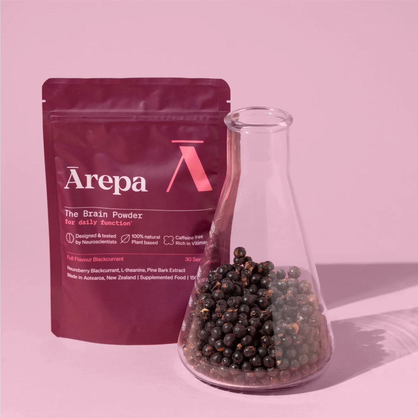 Ārepa Brain Powder for daily function with a lab-style beaker of Neuroberry® blackcurrants, highlighting the supplement’s natural, science-backed ingredients on a pink background.