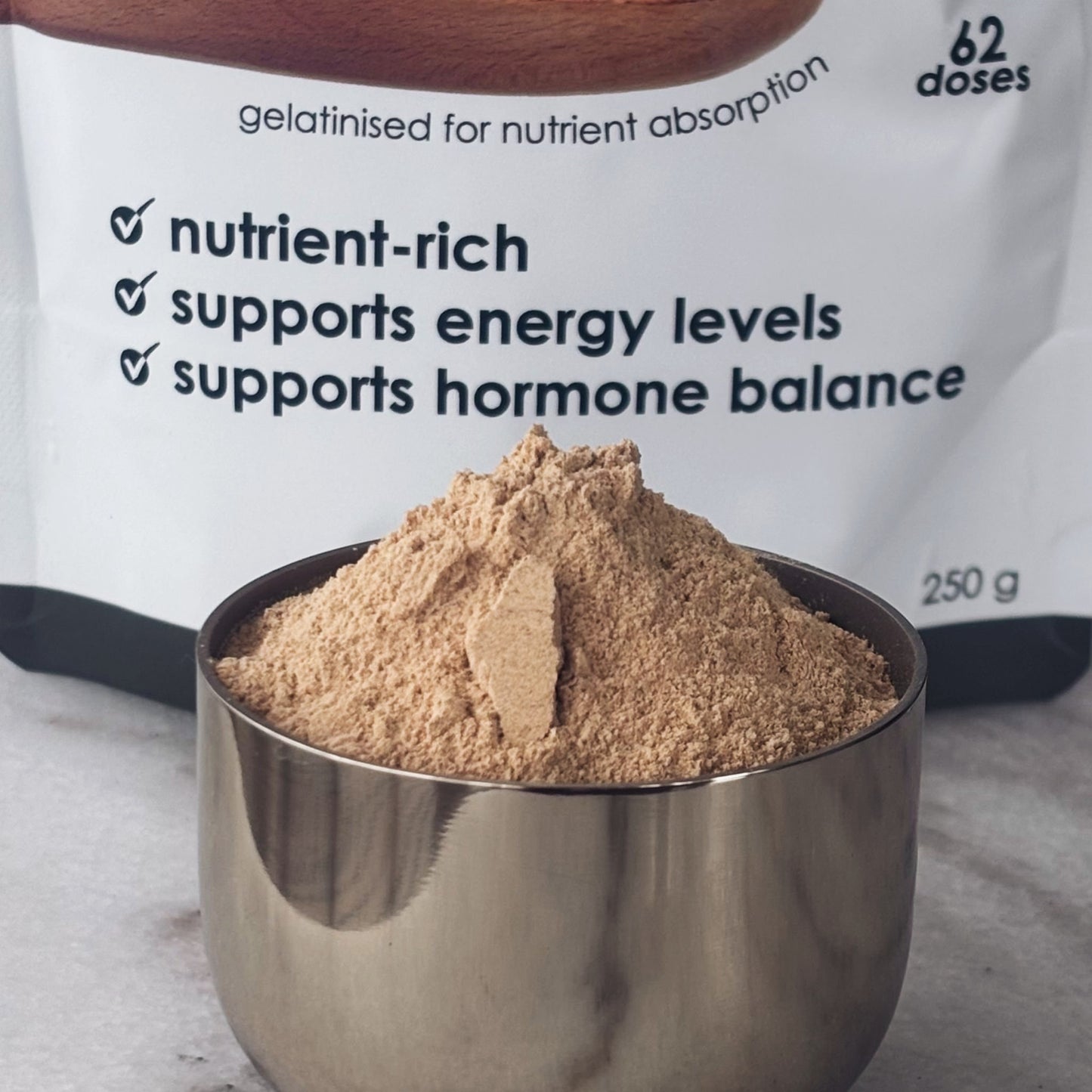 Matakana Superfoods Black Maca Root Gelatinised Powder pouch with the powder also in a gold dish. 