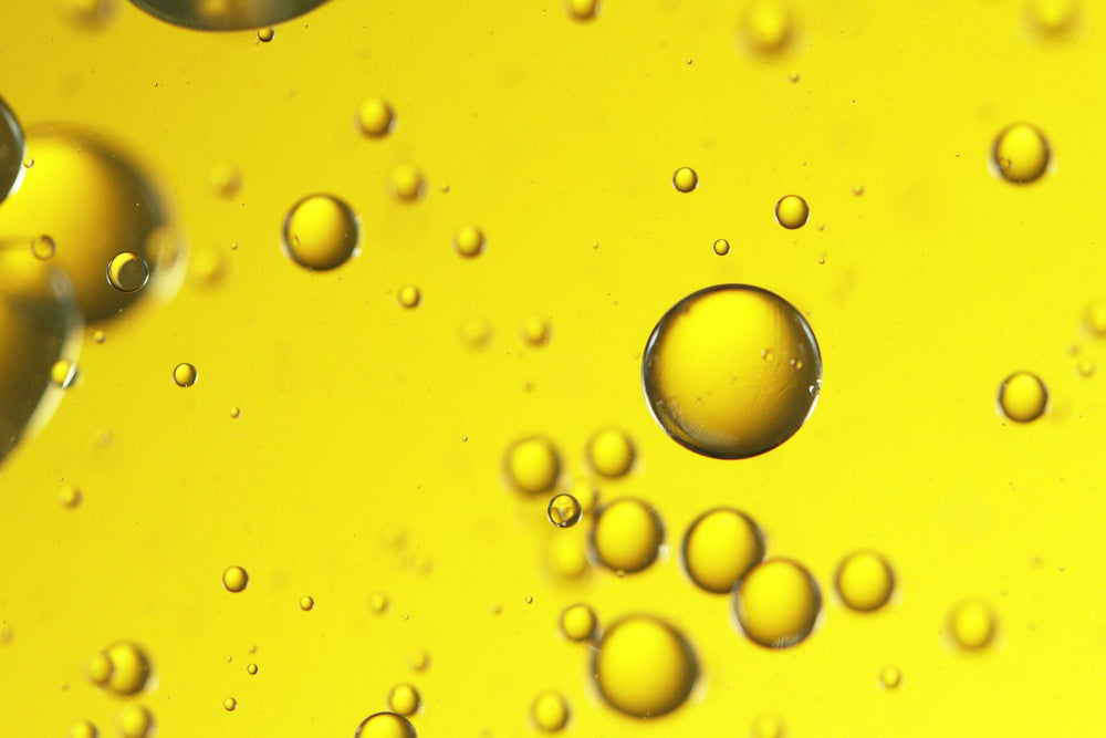 Golden botanical oil droplets suspended in liquid, representing nutrient-rich Cacay Seed Oil valued for its vitamins and skin-renewing properties.