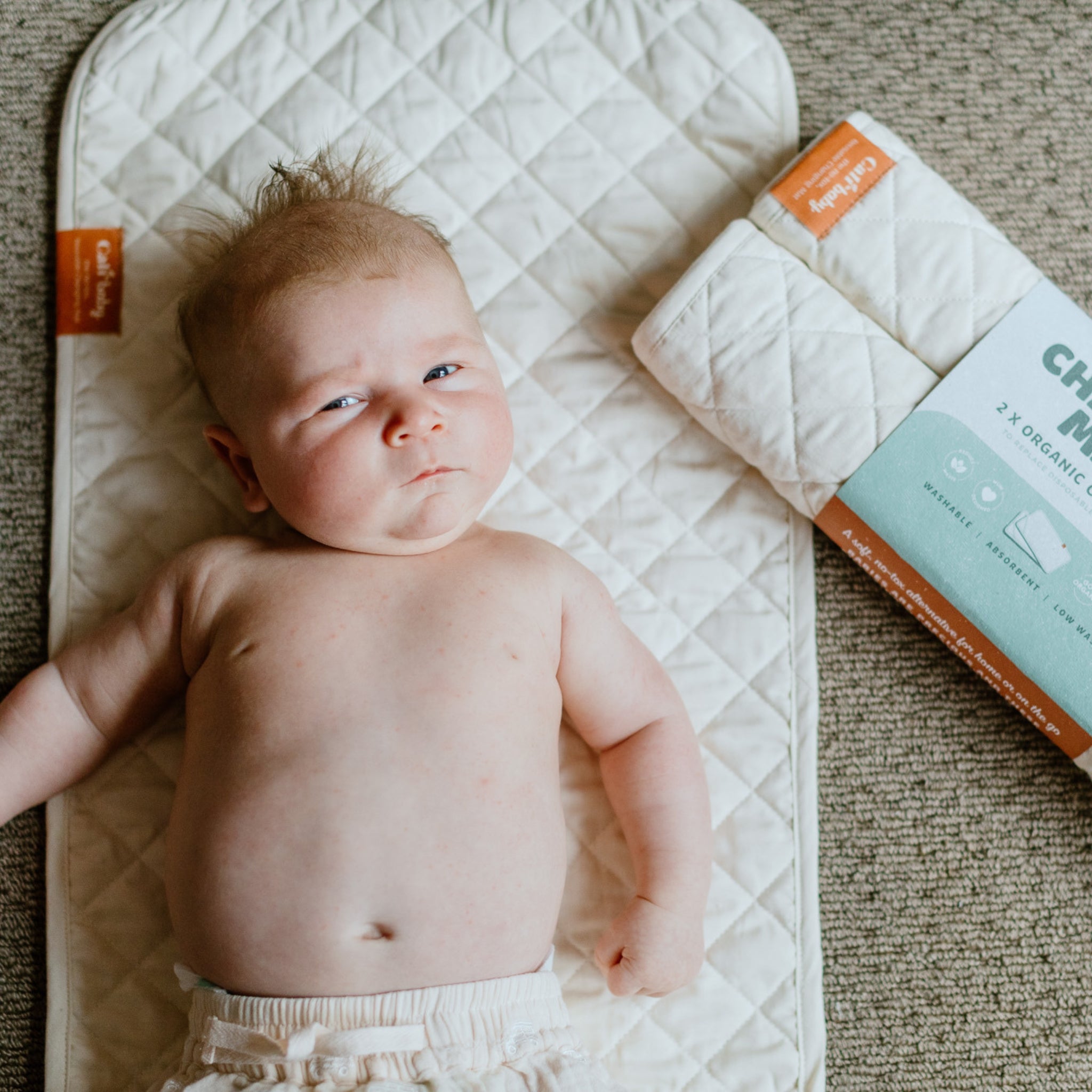 Baby lying  on the CaliWoods 2 pack reusable organic cotton changing mat.
