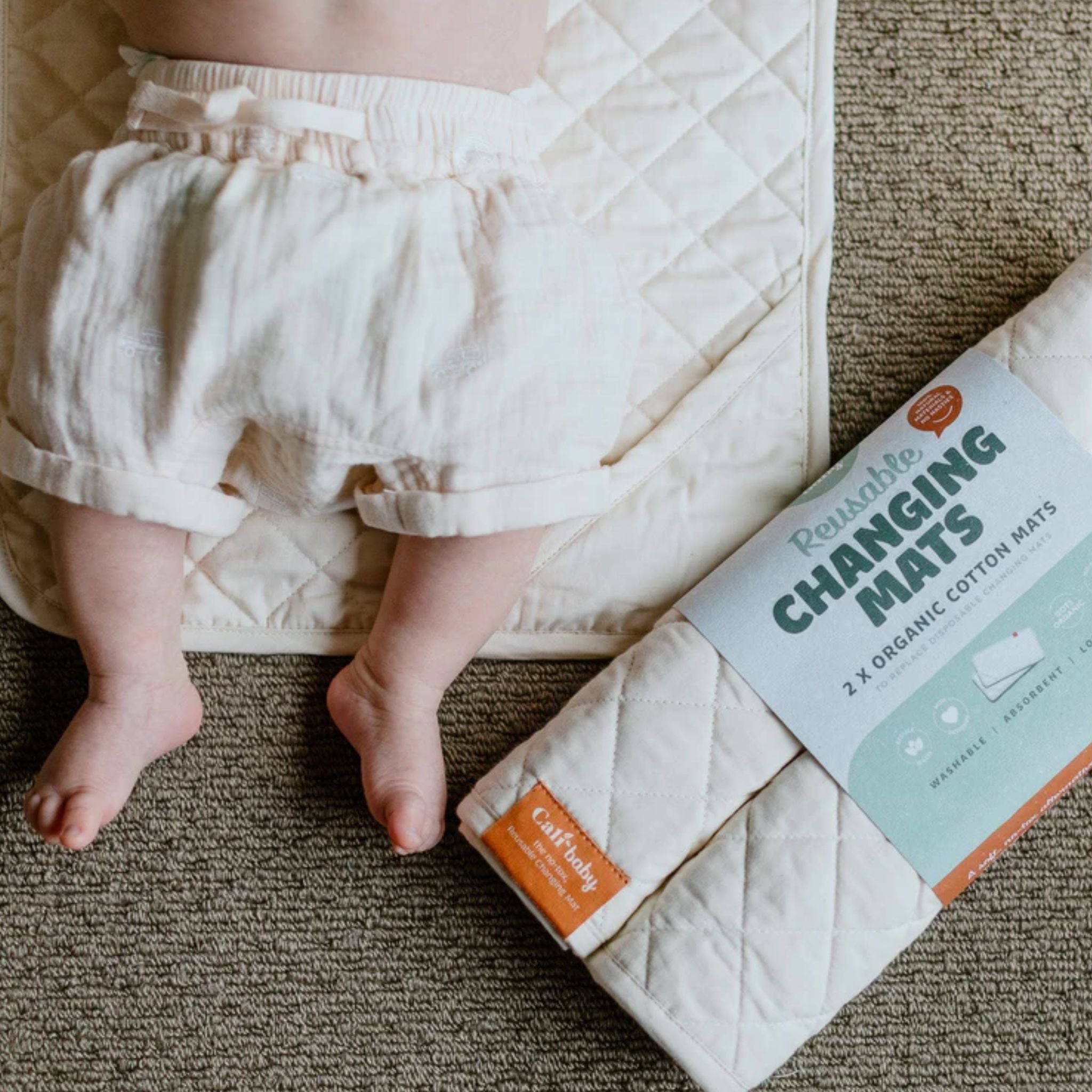 Reusable organic cotton changing mat by CaliWoods  with stash pocket – low waste baby care essential shown with baby legs on quilted mat NZ