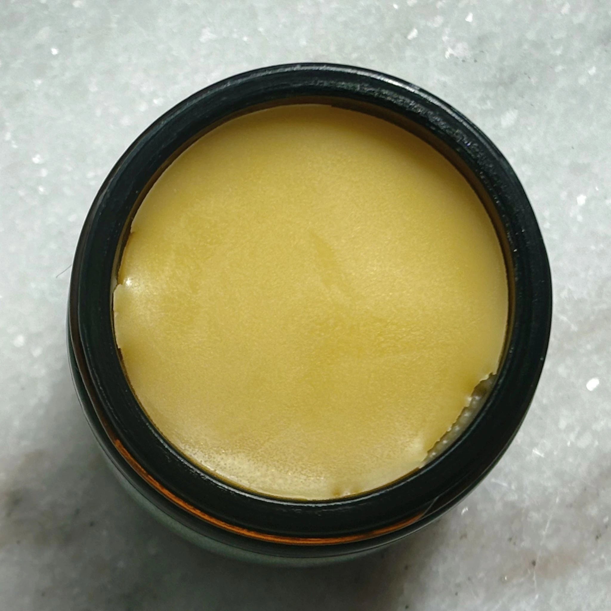 Open jar of Frankie Apothecary Kawakawa Repair Balm showing smooth, golden balm texture for natural skin healing.