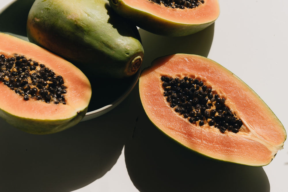 Fresh papaya fruit displaying vibrant orange flesh and enzyme-rich seeds, the natural source of papain used to support gentle skin renewal.