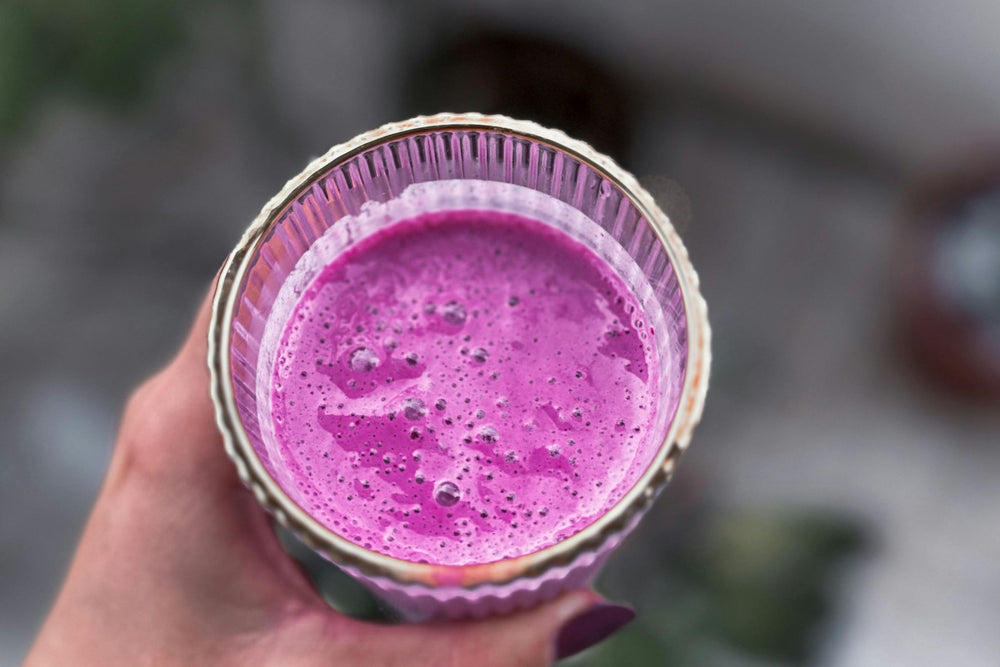 Hand holding vibrant pinky red wellness smoothie.