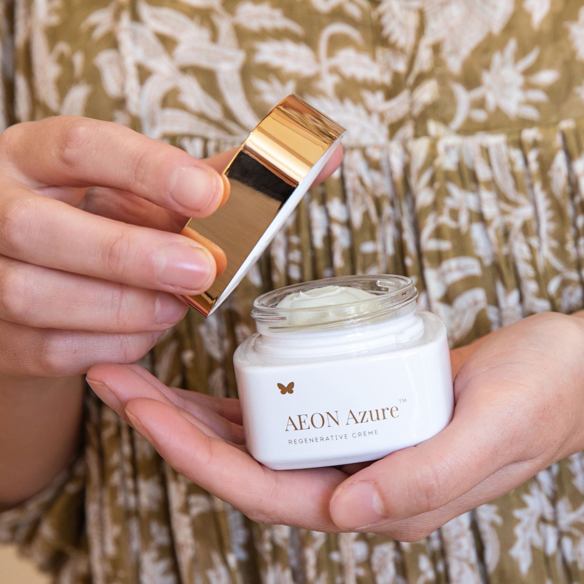 Vanessa Megan AEON Azure Regenerative Cream open jar held in hands with gold lid.
