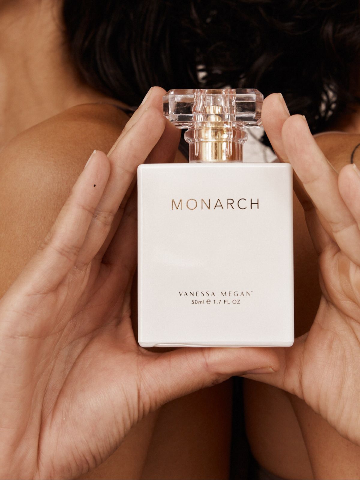 Close-up of two women holding a bottle of Vanessa Megan Monarch Natural Perfume 50ml. Shop this luxury natural fragrance at Intentionally Natural NZ.