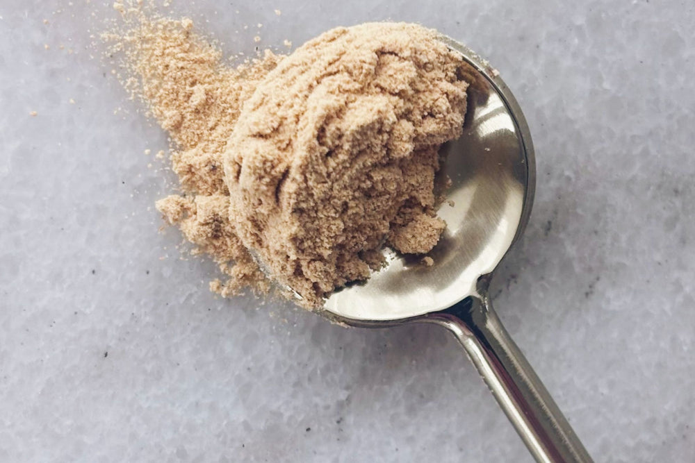 Matakana Superfoods Black Maca Root Gelatinised Powder on gold spoon on marble surface.