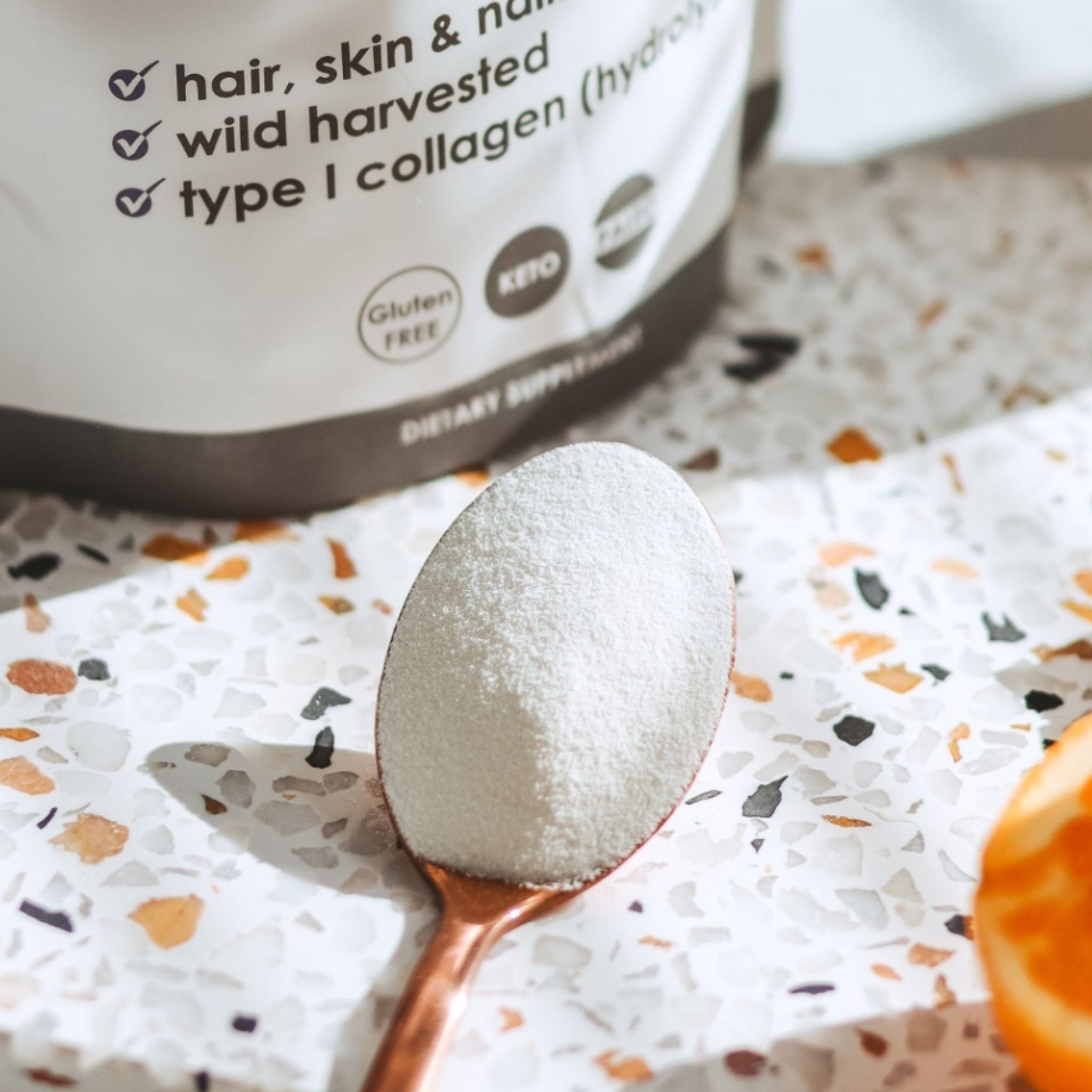  Matakana Superfoods Premium Marine Collagen Peptide Powder on spoon next to pouch and cut citrus.