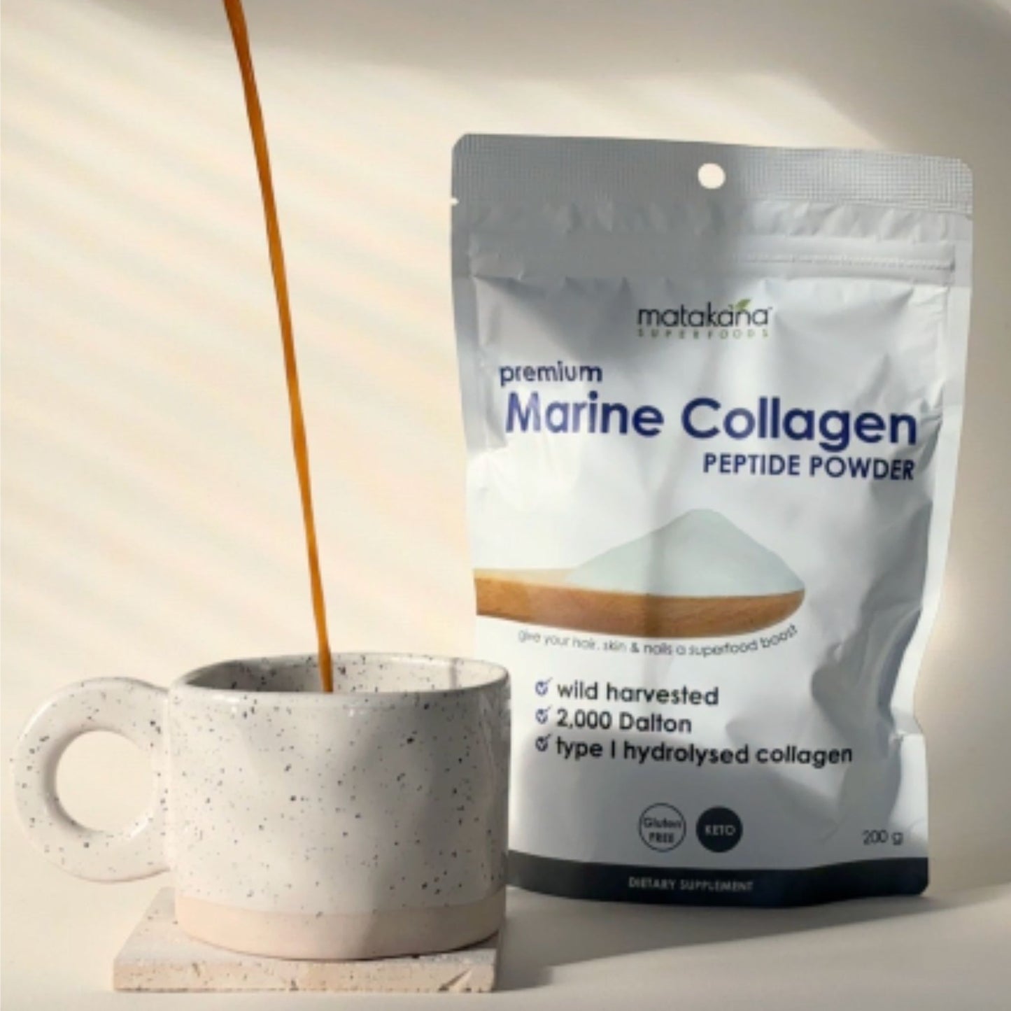  Matakana Superfoods Premium Marine Collagen Peptide Powder pouch  next to a mug of coffee being  poured.