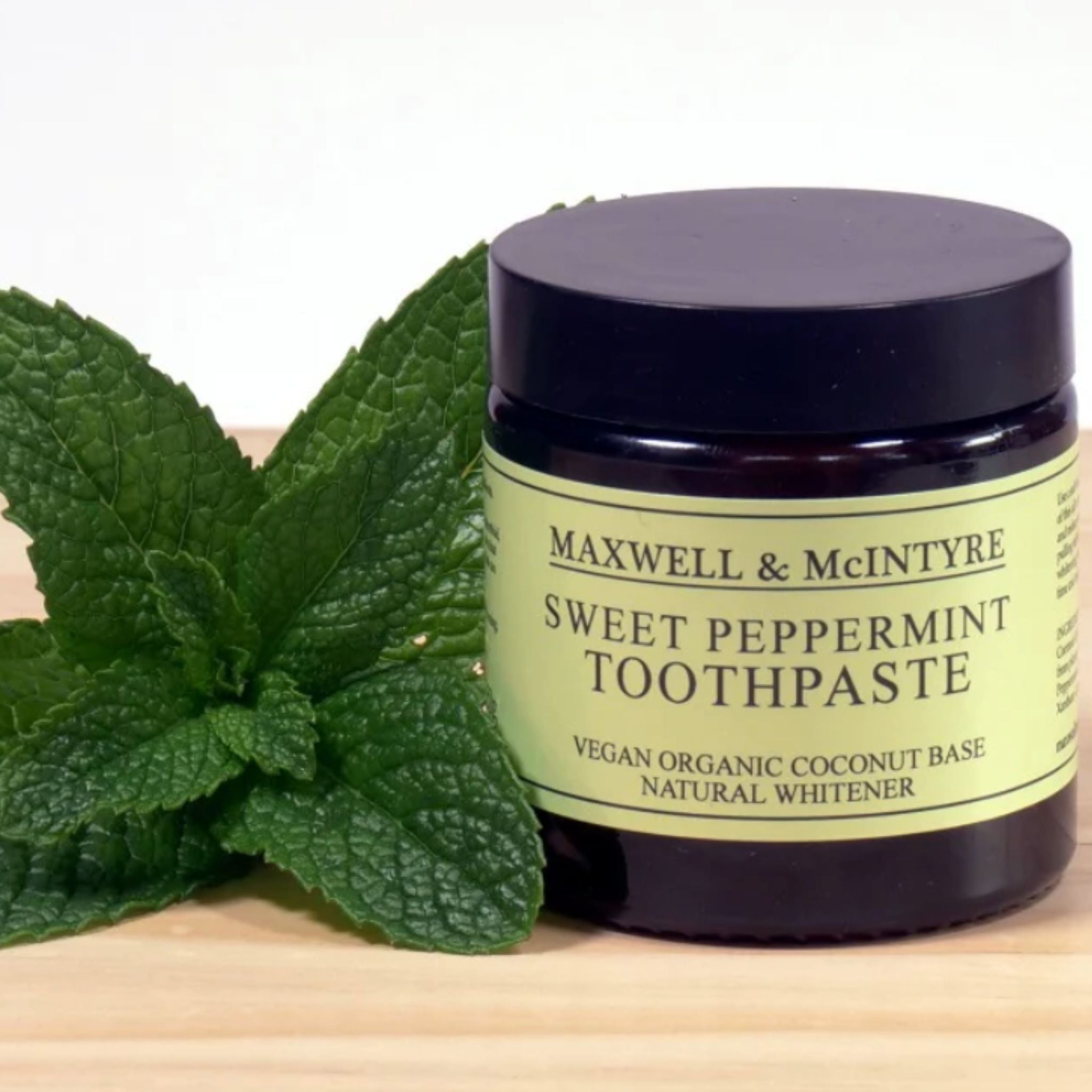 Maxwell & McIntyre Sweet Peppermint Toothpaste with organic coconut oil in amber glass jar with fresh mint leaves.