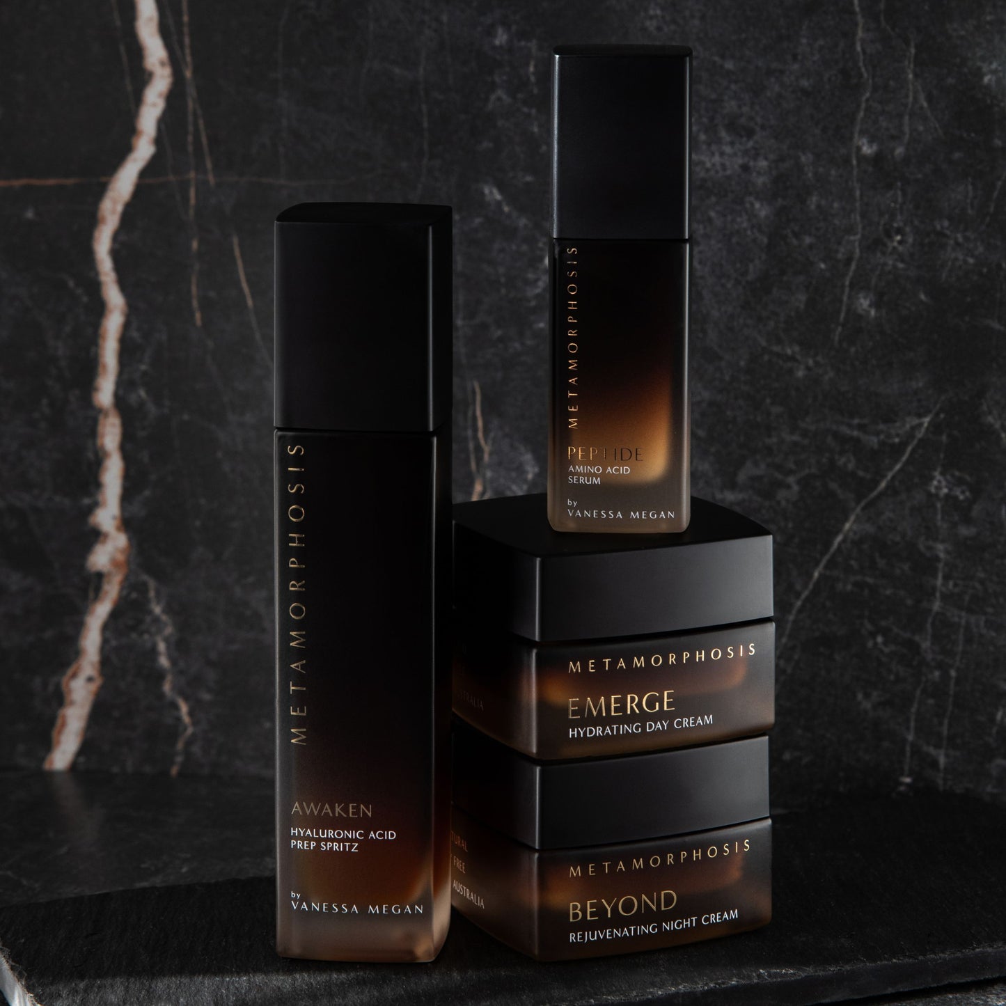 Metamorphosis Awaken Hyaluronic Acid Prep Spritz alongside the Peptide Amino Acid Serum, Emerge Hydrating Day Cream, and Beyond Rejuvenating Night Cream – science-backed, 100% natural, clinically proven skincare for peri to post menopause, styled on a dark marble surface.