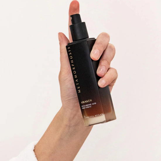 Womens hands spraying the  Metamorphosis Awaken Hyaluronic Acid Prep Spritz. A 100% natural Hyaluronic Acid face mist skincare product.