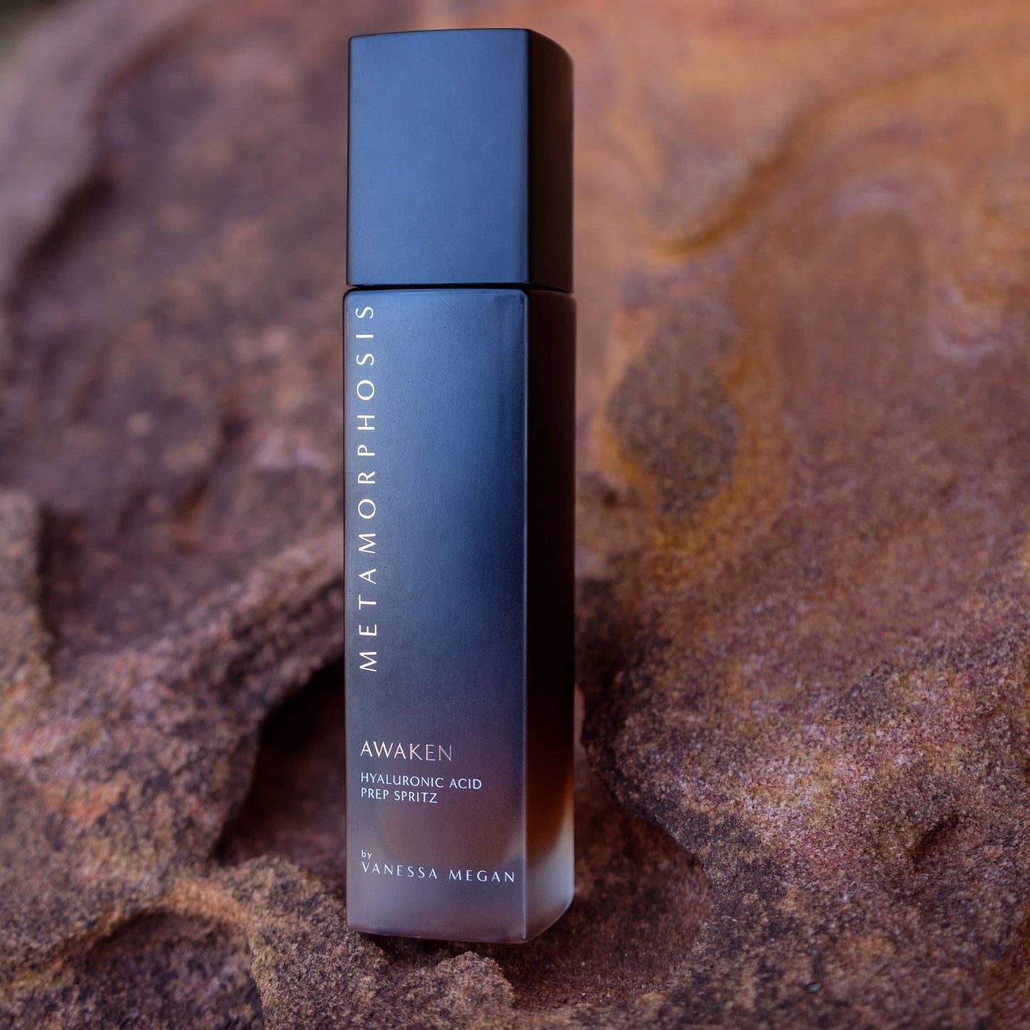 Metamorphosis Awaken Hyaluronic Acid Prep Spritz by Vanessa Megan placed on textured natural rock, highlighting its natural, skin-quenching hydration benefits and connection to earth-derived beauty.