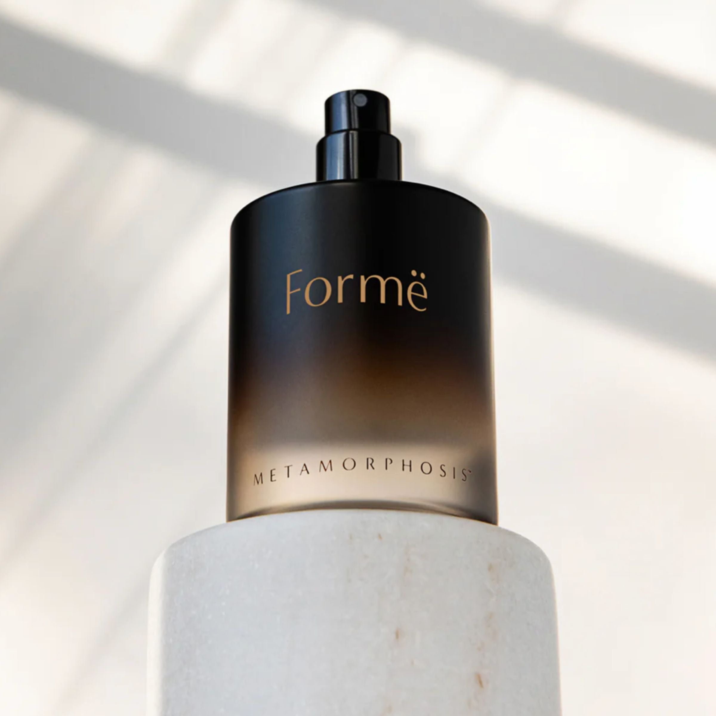 Metamorphosis Formë [for-MAY] 100% natural aromatherapeutic perfume by Vanessa Megan, captured with the spray top revealed and warm, natural light casting soft shadows.