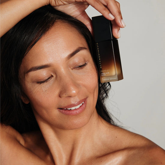 Women holding Vanessa Megan’s Metamorphosis Peptide Amino Acid Serum beside her radiant skin.