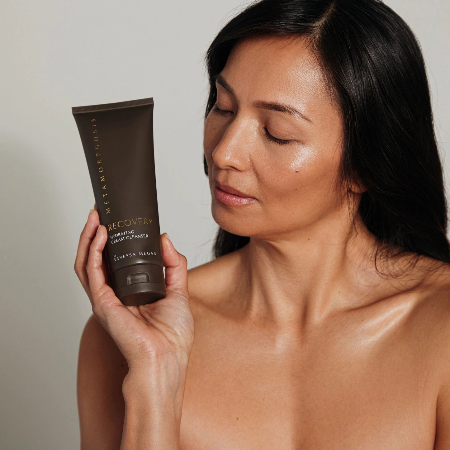 Women with luminous, healthy skin holding the Recovery Hydrating Cream Cleanser, formulated to soothe and nourish hormonally sensitive skin during menopause and beyond.