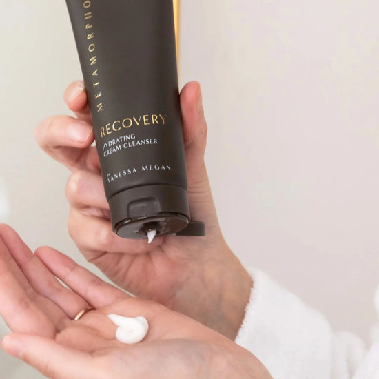Squeezing the Recovery Hydrating Cream Cleanser into the palm, showcasing its creamy texture and nourishing formula made for peri to post menopausal skin.