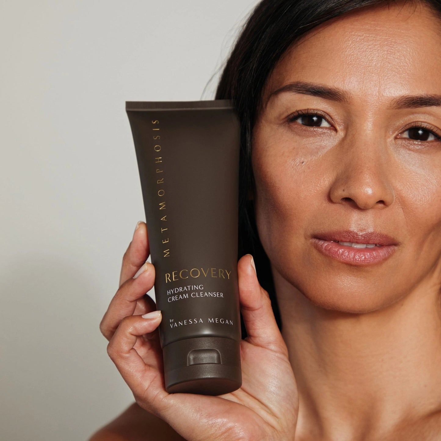 Close-up of women with radiant skin beside the Metamorphosis Recovery Hydrating Cream Cleanser, a natural face cleanser crafted for mature, reactive, or dry skin.