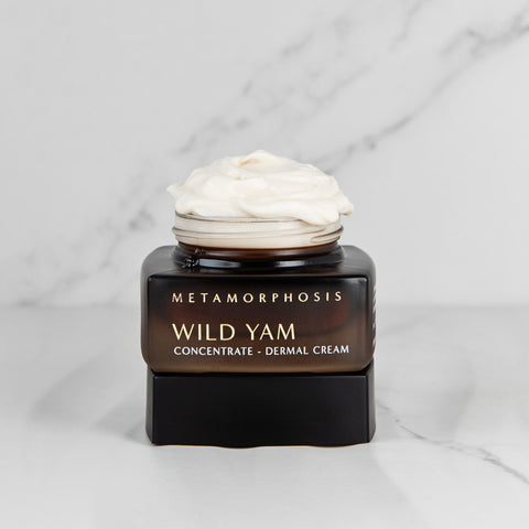 Metamorphosis Skincare Wild Yam Concentrate Dermal Cream jar open on lid with cream  over flowing over the jar on a marble background.