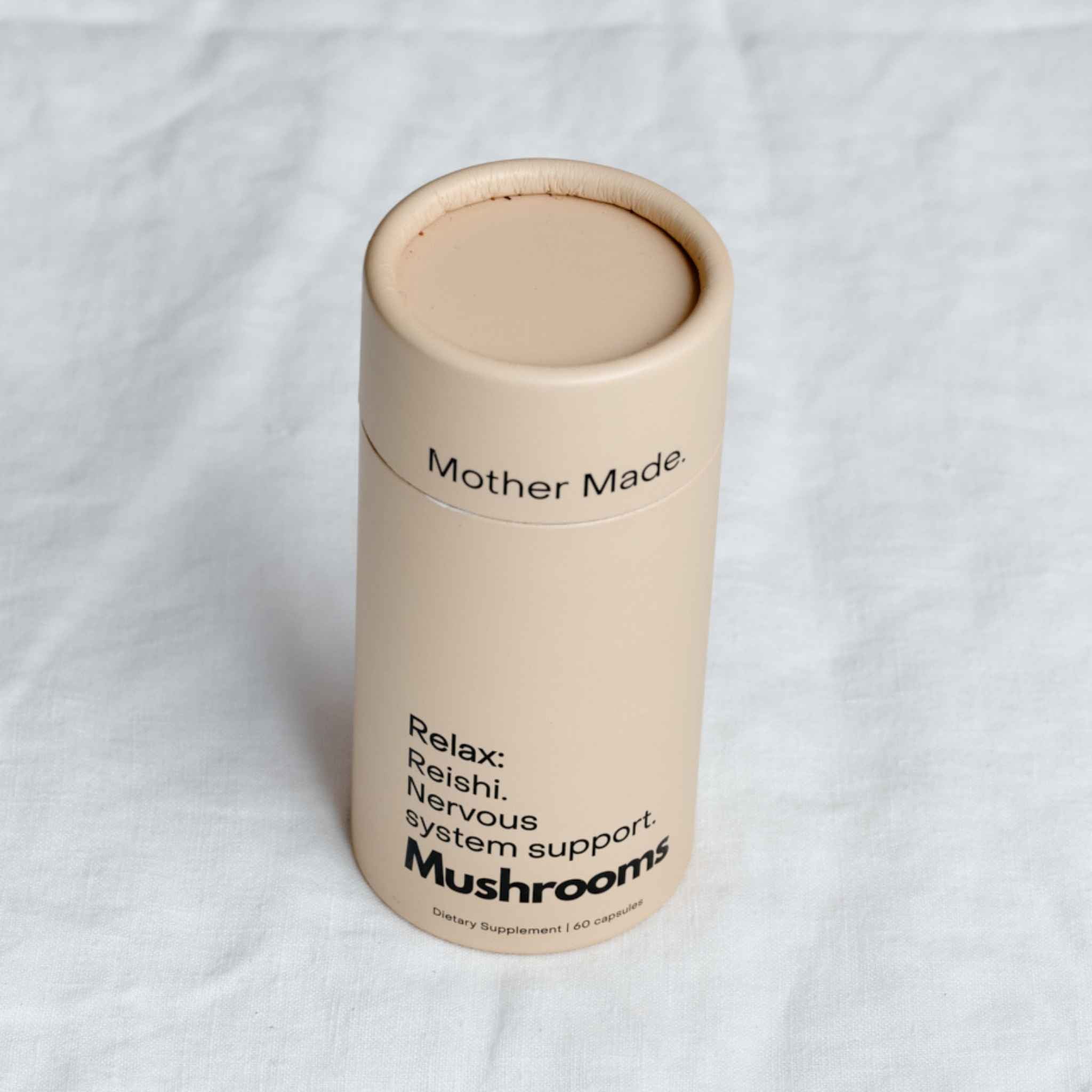 Mother Made Relax Reishi Capsules in a recyclable cardboard canister on a linen tablecloth, a mushroom supplement for nervous system support