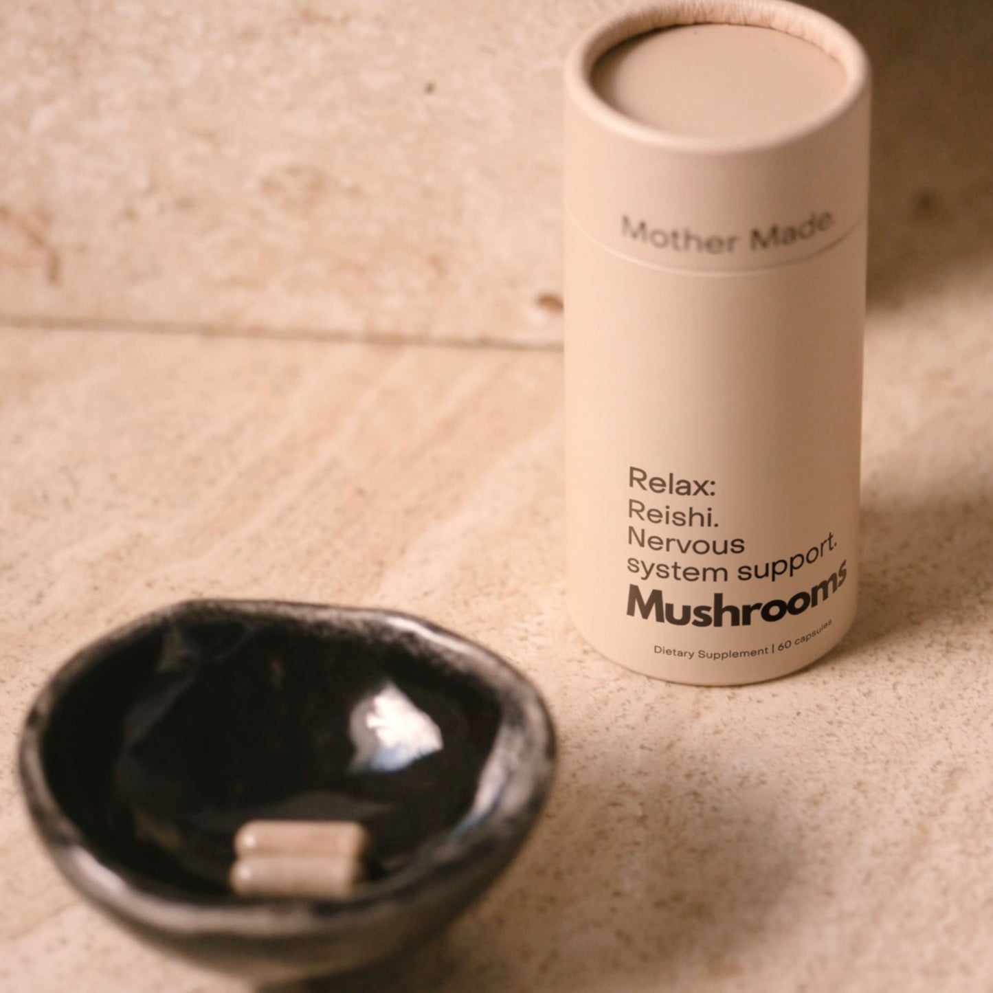 Mother Made Reishi mushroom capsules beside a ceramic dish.