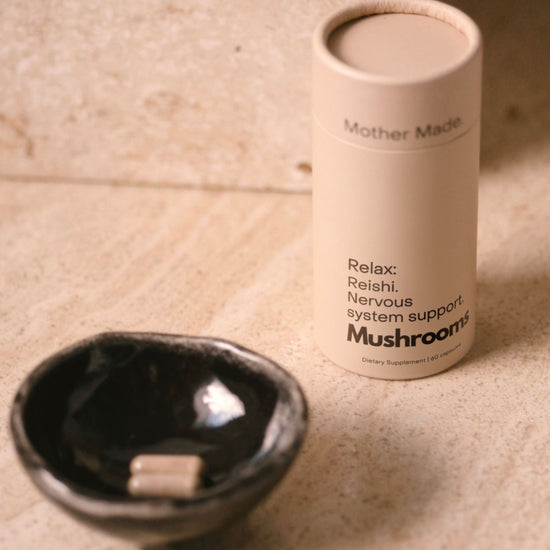 Mother Made Reishi mushroom capsules beside a ceramic dish.