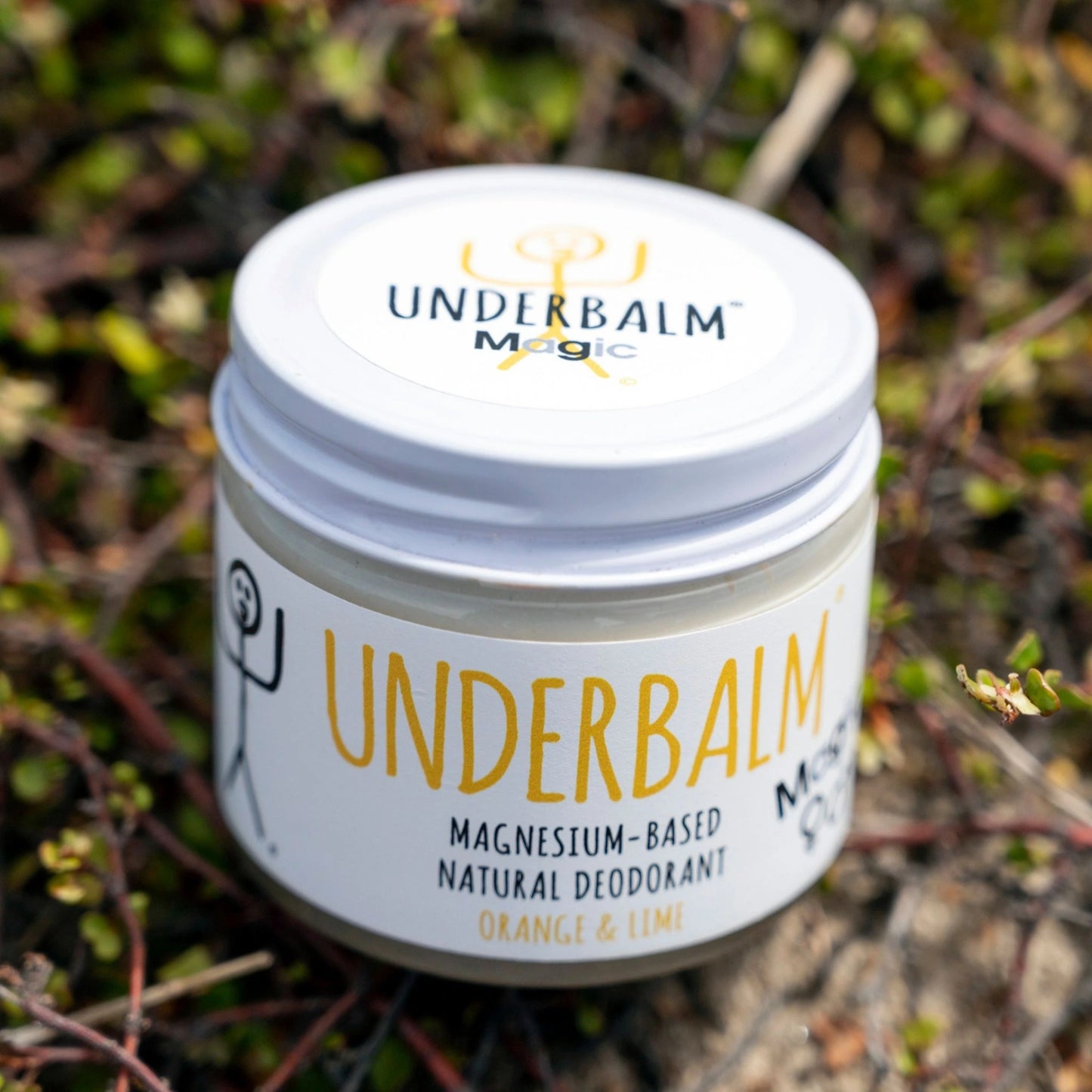 No3 Underbalm Magic Orange & Lime, a magnesium-based natural deodorant in a glass jar, placed on a bed of fresh greenery.