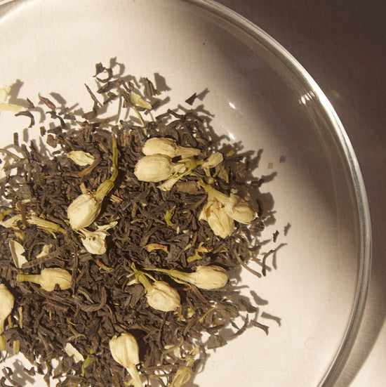 On Sundays Loose leaf blend of  the organic jasmine flowers and premium green tea leaves in a glass dish, highlighting the purity and natural composition of On Sundays Green Jasmine Tea.