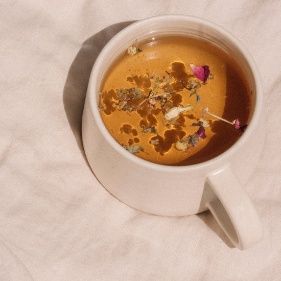 On Sundays Dreamland organic loose leaf herbal sleep tea brewed in ceramic mug with floating chamomile rose and lavender.