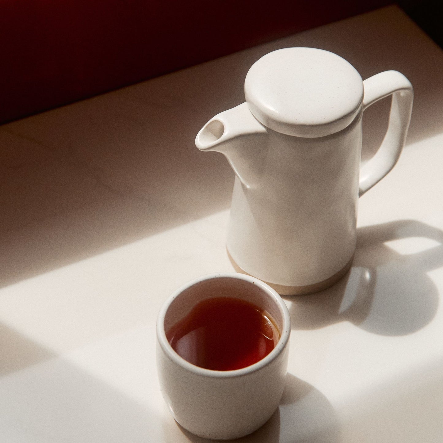 On Sundays Earl Grey loose leaf black tea served in white ceramic teapot and cup in warm natural light/