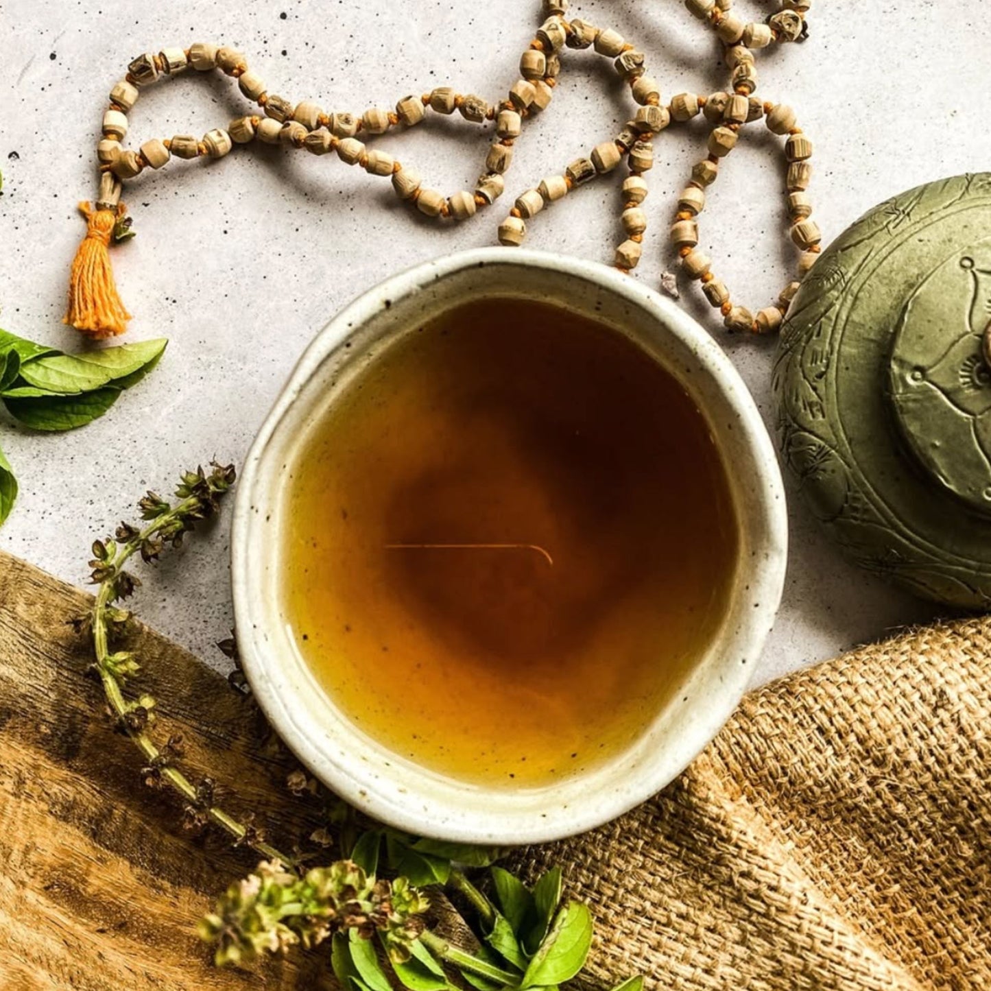 Organic India Tulsi herbal tea brewed in a mug warm amber infusion with fresh tulsi leaves natural wellness tea serving scene.