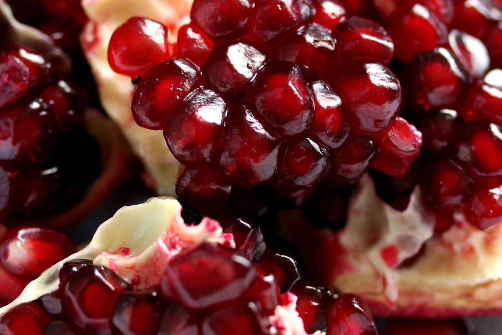 Pomegranate fruit close up with vibrant red arils, antioxidant rich key ingredient for natural beauty, skincare, health and wellness products.