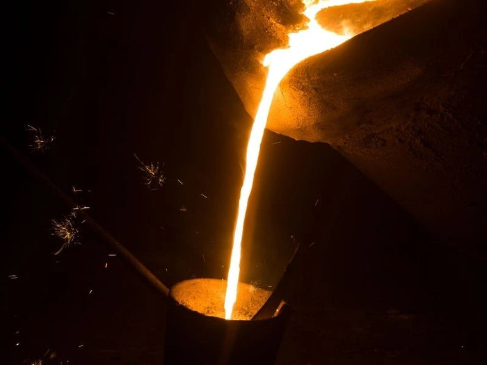 Molten Kansa metal being poured during traditional crafting process.