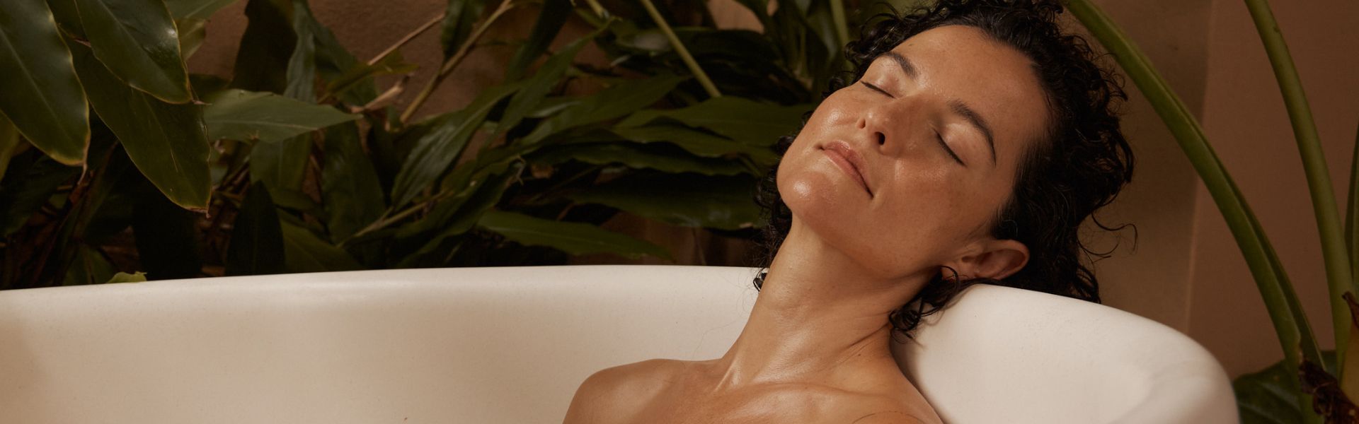 Woman relaxing in a bathtub with plants in the background
