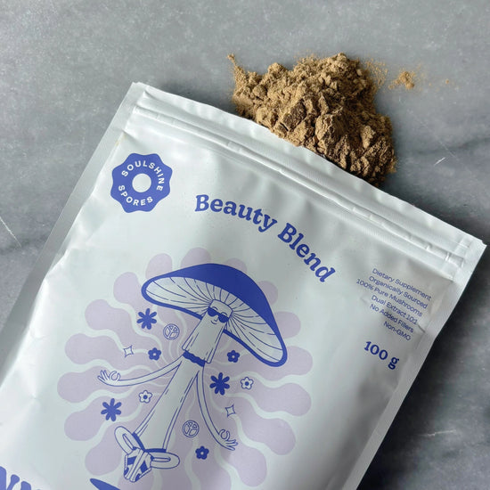 A pouch of Soulshine Spores InnerBloom Beauty Blend with finely ground mushroom powder spilled onto a marble surface. This 100% organic medicinal mushroom blend, featuring Tremella, Shiitake, and Chaga at Intentionally Natural NZ