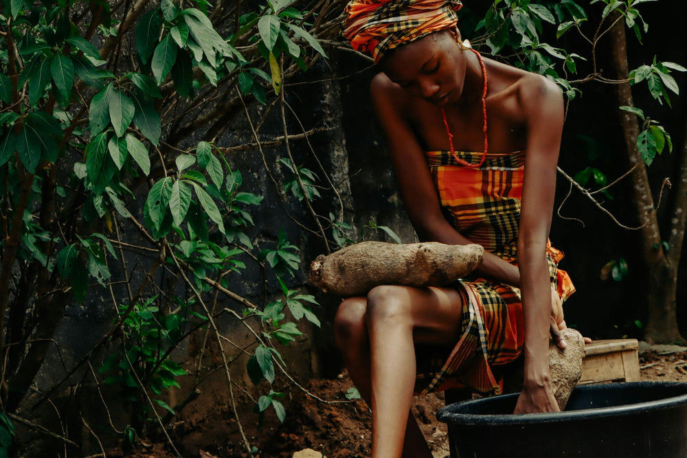 A woman in a colorful dress traditionally harvesting wild yam  (Dioscorea villosa) in rural setting