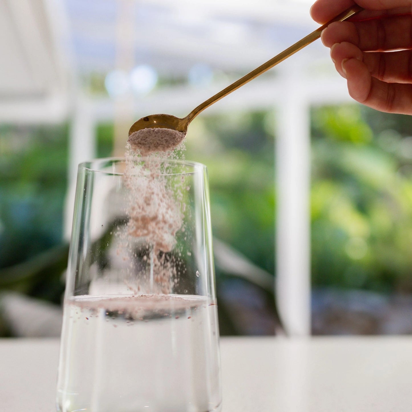Spoonful of Vanessa Megan Astaxanthin and Marine Collagen Skin Boost powder being added to water, bioavailable marine collagen peptides with antioxidant-rich astaxanthin for skin glow.