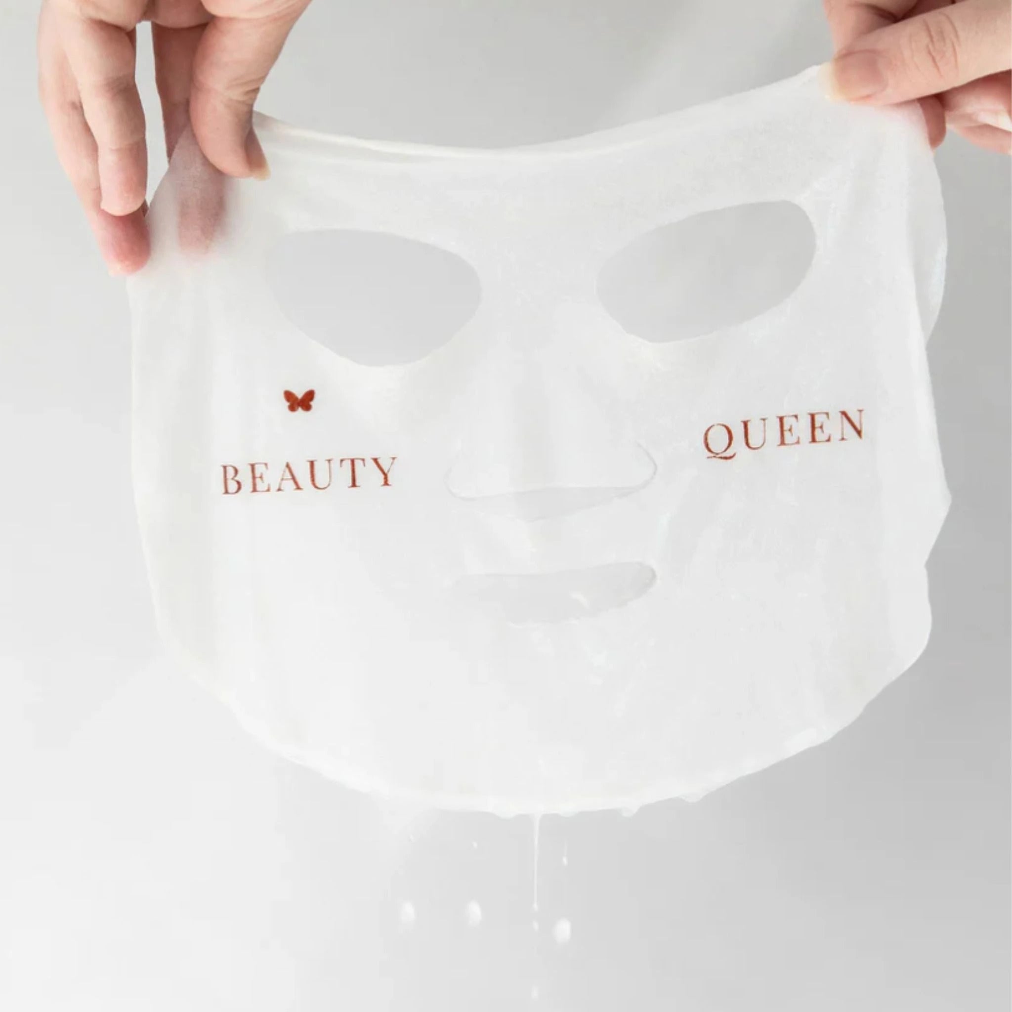 Hands holding the Hydrating Blue Tansy and Cypress Soothing Sheet Mask from Vanessa Megan – saturated sheet held mid-air.
