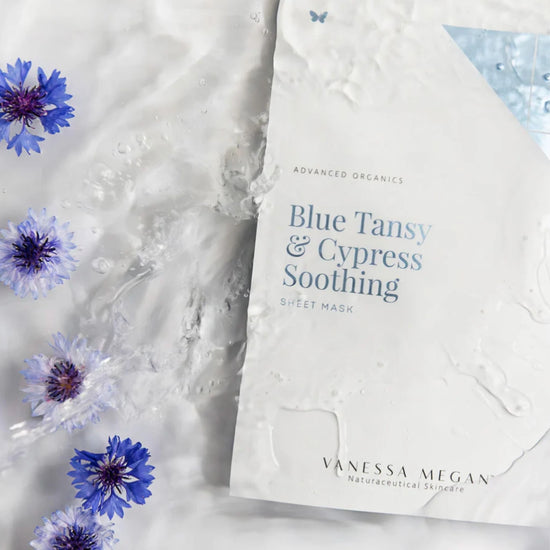 Vanessa Megan Blue Tansy and Cypress Soothing Sheet Mask displayed in a water flat lay with calming cornflowers – natural anti-redness solution for sensitive skin.
