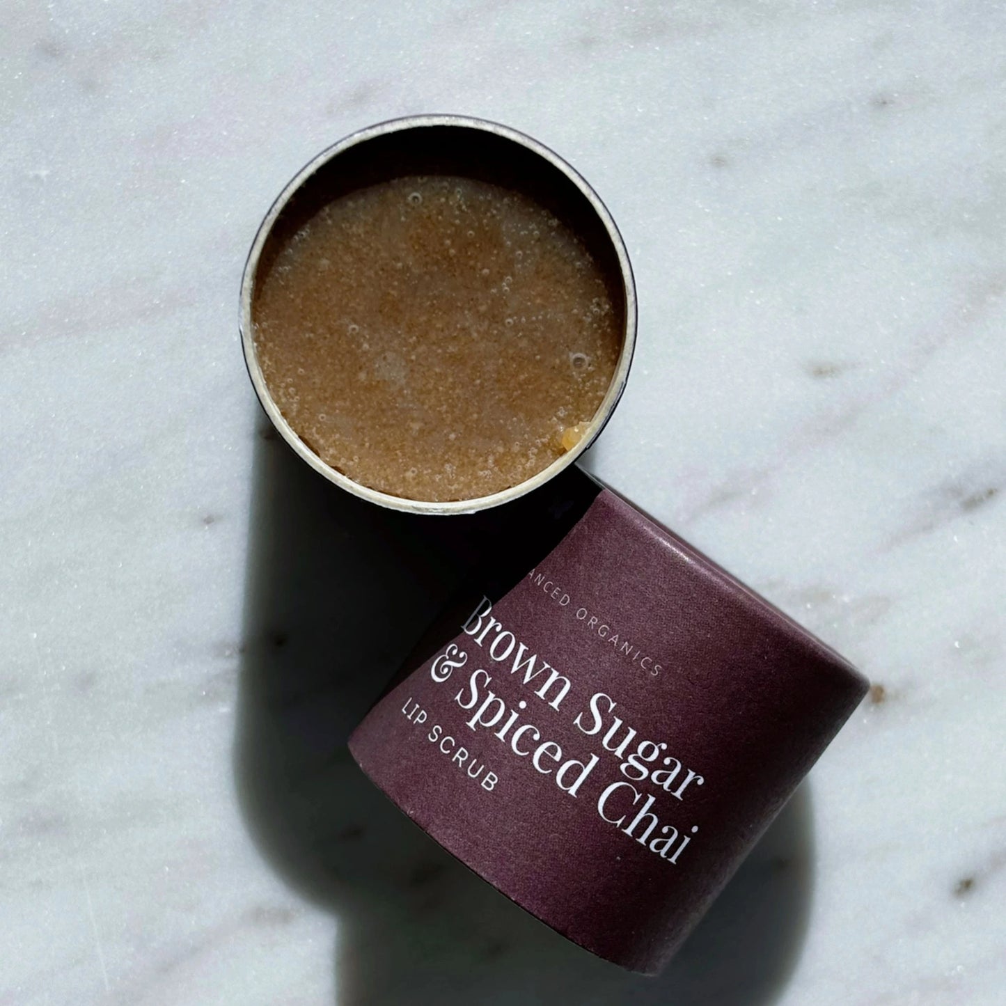 Open tub of Vanessa Megan Brown Sugar & Spiced Chai Lip Scrub on marble at Intentionally Natural.