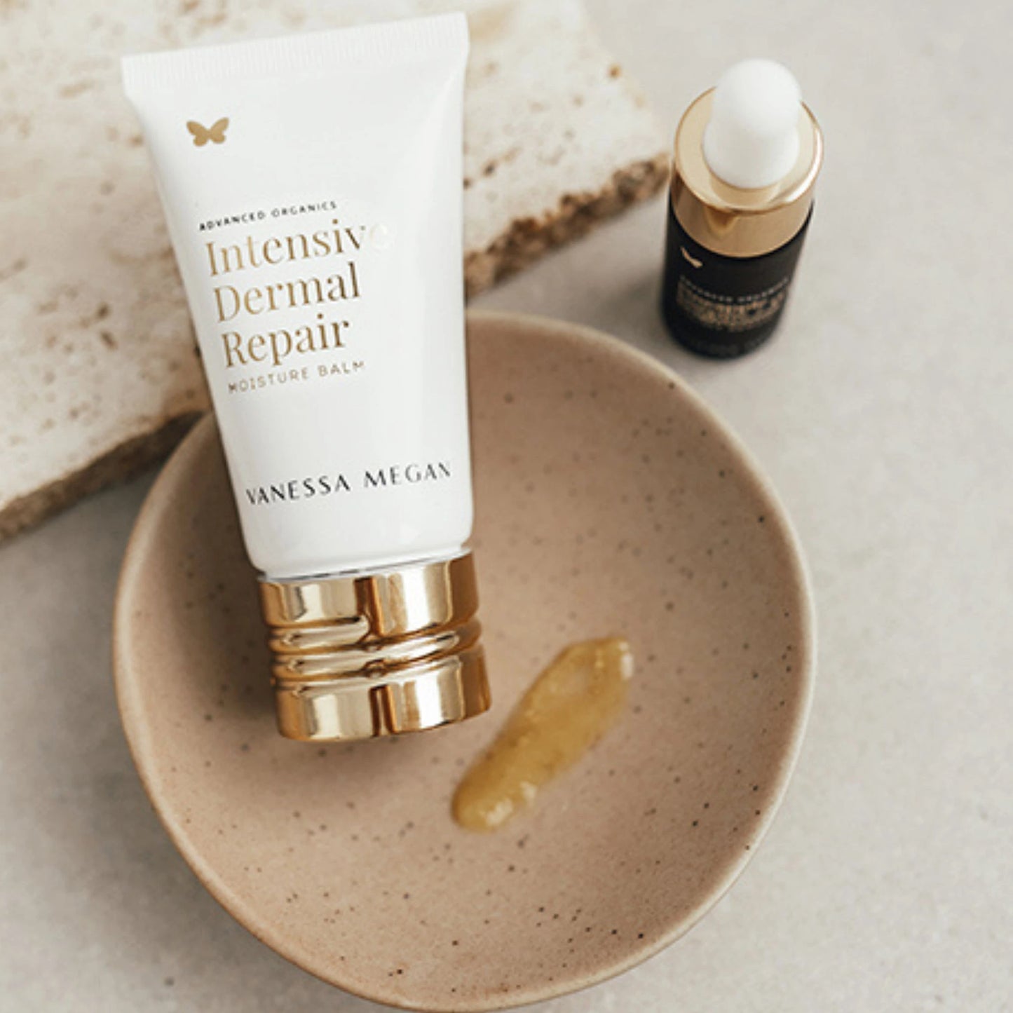 Vanessa Megan Intensive Dermal Repair Balm pictured in bowl alongside the Pineapple Enzyme + HA Brightening Eyelift Serum