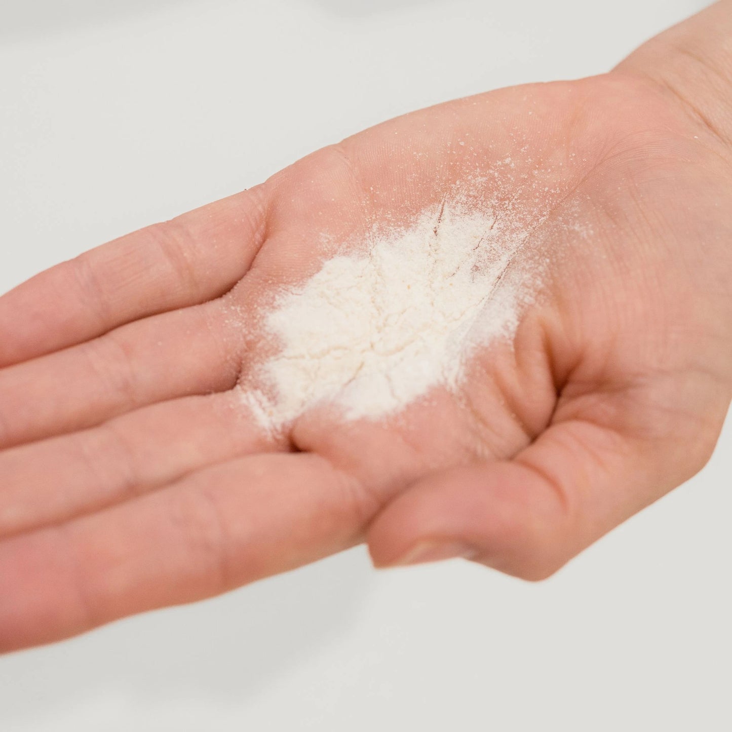 Close-up of Vanessa Megan Prebiotic + C Exfoliating Powder in hand showing ultra-fine, active botanical texture.